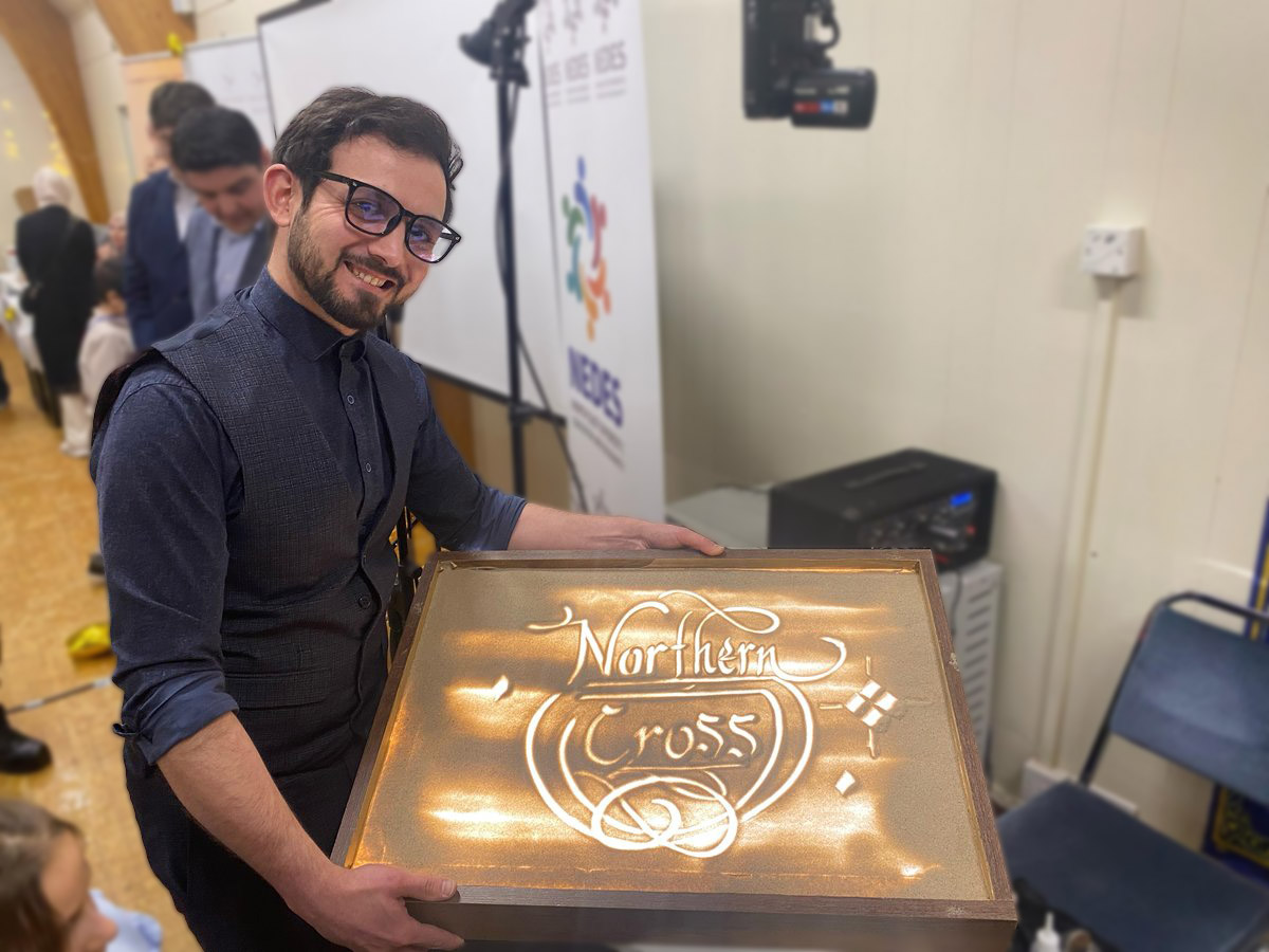 Bilal Köse with a sand calligraphy artwork